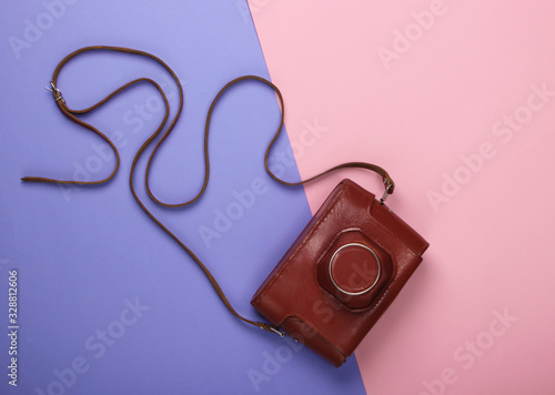 Retro camera in a leather case on a pink-purple pastel background. Top view