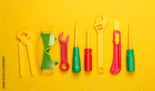 Set of children's toy work tools on yellow background. Top view photo