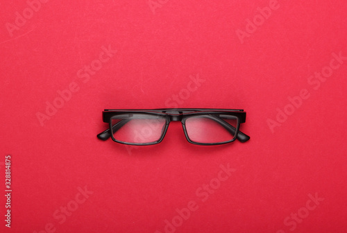 Classic eyeglasses on red background. Top view.