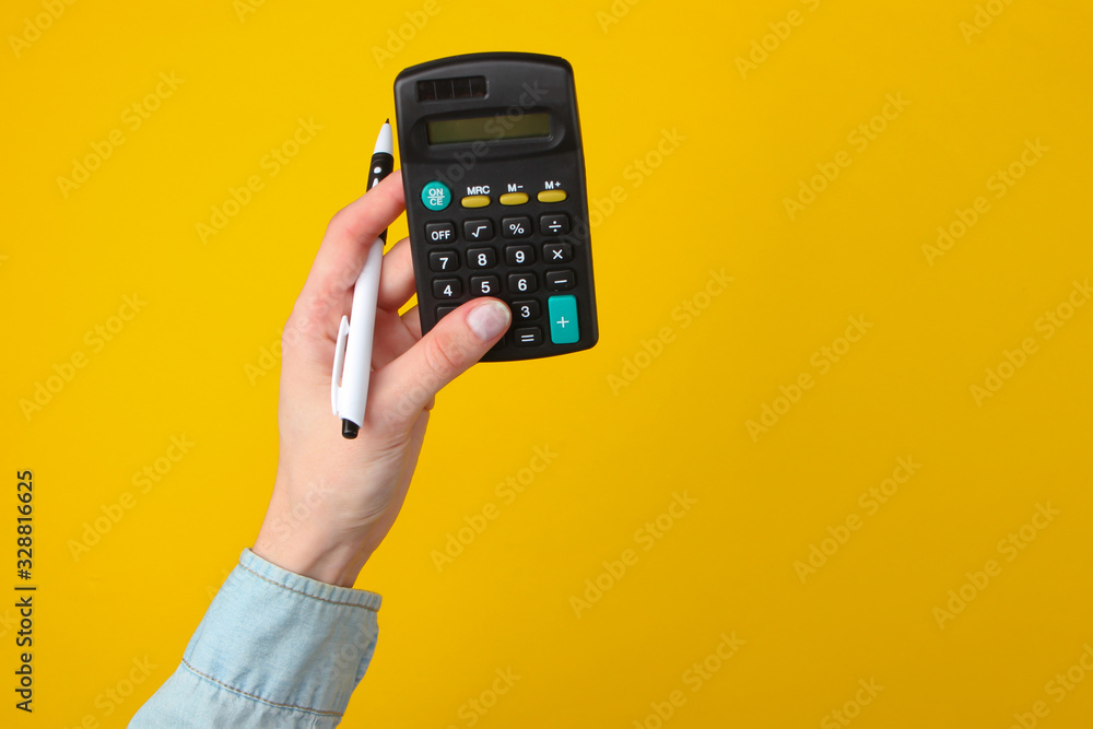 Female hands count calculator on a yellow background. Top view Female hands count calculator on a yellow background. Top view