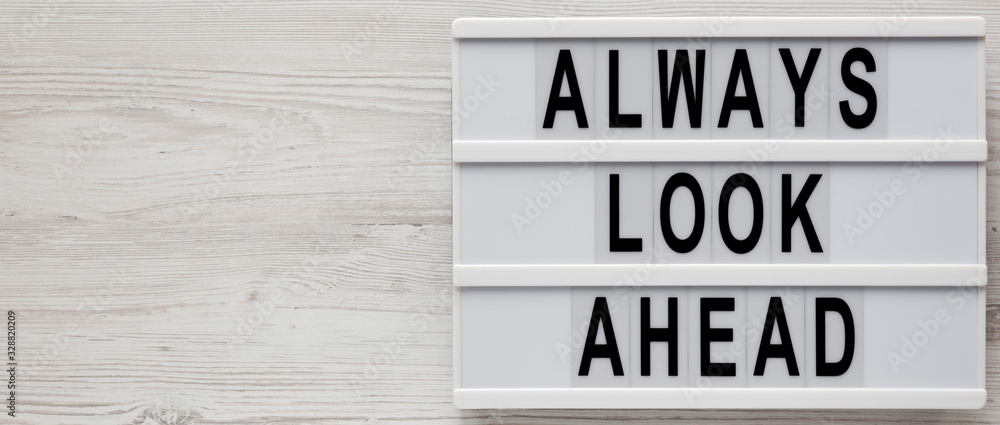 'Always look ahead' words on a lightbox on a white wooden surface, top view. Overhead, from above, flat lay. Space for text. 'Always look ahead' words on a lightbox on a white wooden surface, top view. Overhead, from above, flat lay. Space for text.
