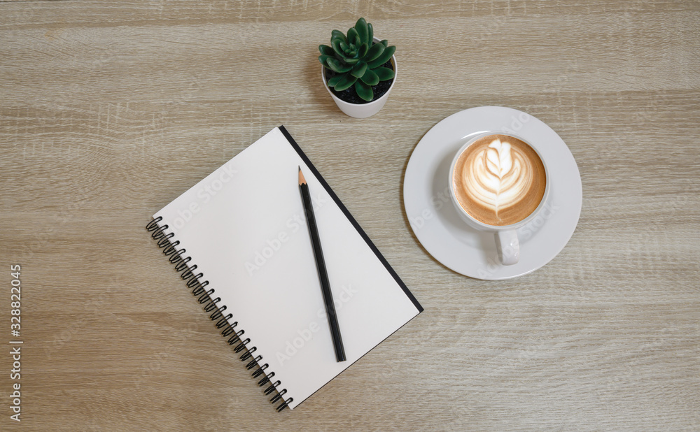 top view of notebook next to a pen and cup of coffee on wooden table with copy space. top view of notebook next to a pen and cup of coffee on wooden table with copy space.