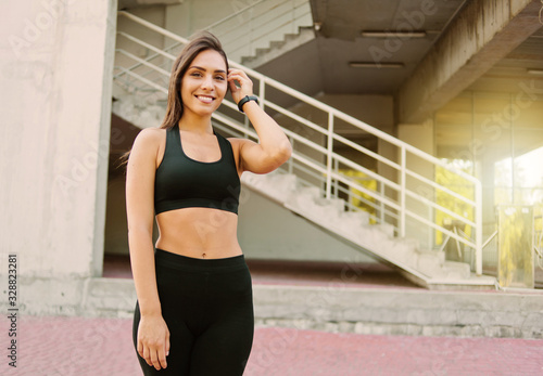 Portrait of attractive sport woman in sportswear posing outdoors at urban environment