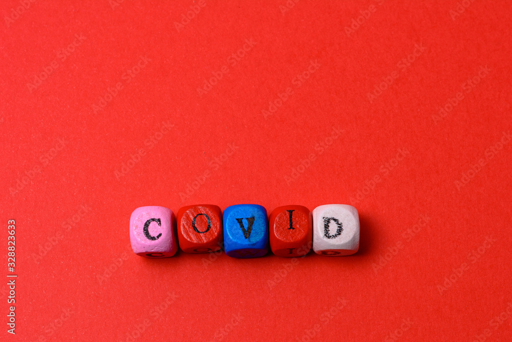 The inscription COVID-19 with wooden cubes on a red background. The inscription COVID-19 with wooden cubes on a red background.