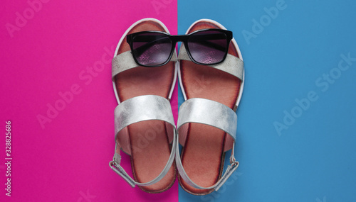Creative summer beach flat lay. Leather women's sandals, sunglasses on colored background. Top view