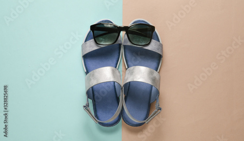 Creative summer beach flat lay. Leather women's sandals, sunglasses on colored background. Top view