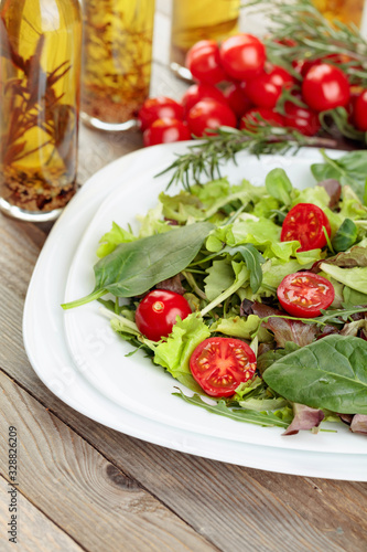 Fresh mixed salad with cherry tomatoes on white plate.