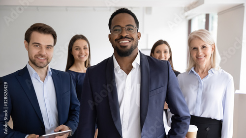 Group portrait of smiling motivated multiracial businesspeople stand show unity and support, happy multiethnic diverse colleagues coworkers posing together in office, teamwork, leadership concept