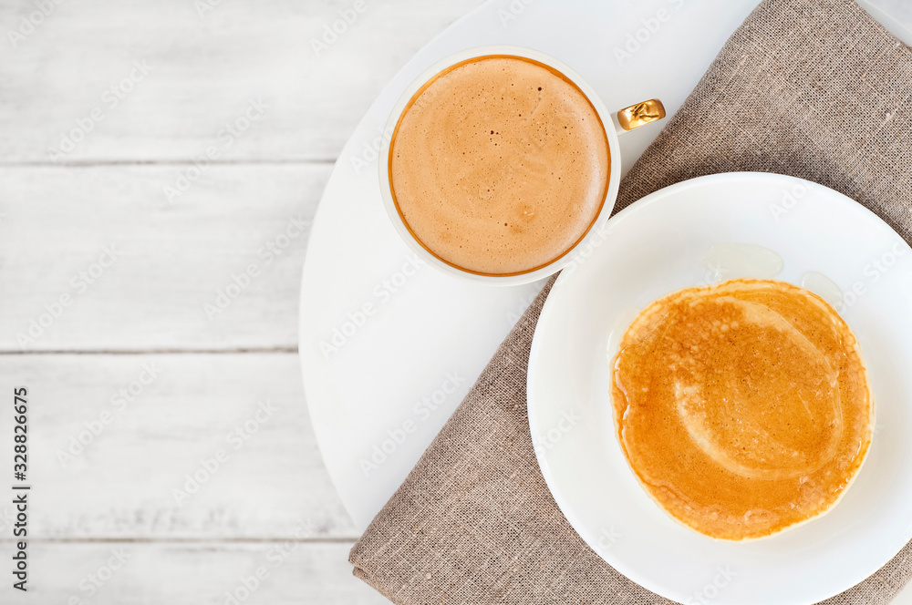 Cup cream coffee or latte, pancakes, tablecloth on a white coffee table wood background. Good morning. Tasty breakfast concept.  Top view. Flat lay