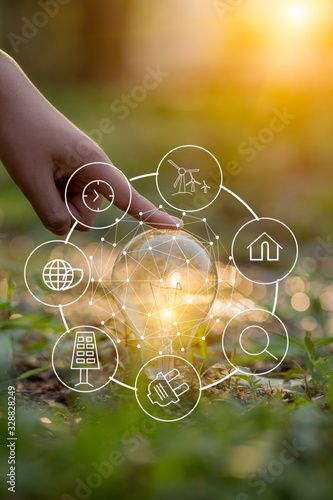 hand holding light bulb against nature, icons energy sources for renewable © aekachai