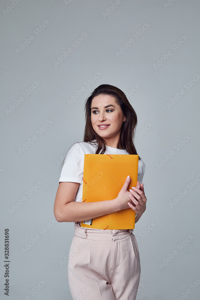 girl student stands with an orange folder thoughtfully and smile girl student stands with an orange folder thoughtfully and smile