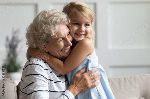 Obraz na plátně Smiling cute little preschooler girl hug overjoyed senior grandmother show love