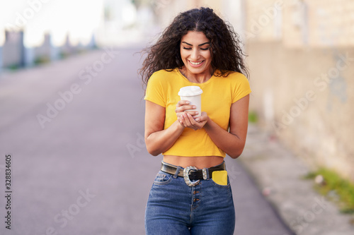 Arab girl walking across the street with a take-away coffee