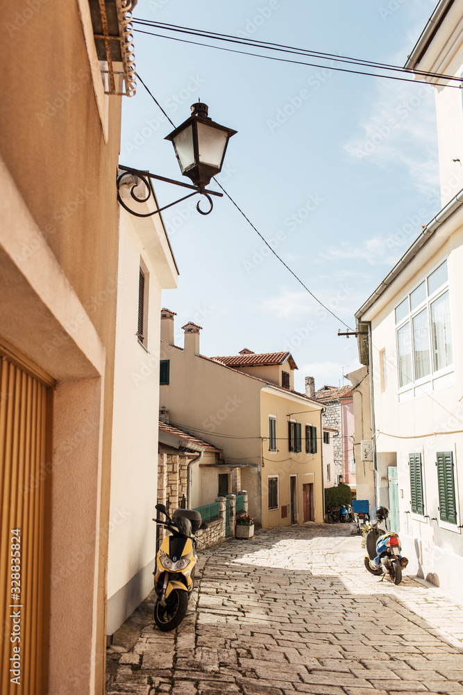 Obraz premium Travel summer concept. Old city view of Europe, Croatia, Istria region, Rovinj. Empty street with old buildings and motorbikes at sunny day.