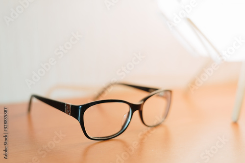black-rimmed glasses under a table lamp