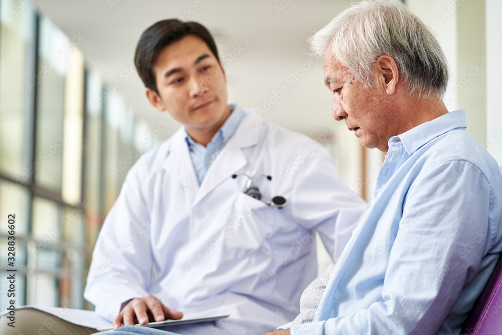 young asian doctor explaining test result and diagnosis to senior man in hospital hallway young asian doctor explaining test result and diagnosis to senior man in hospital hallway