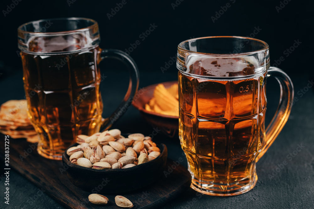 Variety of snacks and mug of light beer. Cheese balls, chips and nuts with two mugs of lager. Bar table. Restaurant, pub, oktoberfest food Variety of snacks and mug of light beer. Cheese balls, chips and nuts with two mugs of lager. Bar table. Restaurant, pub, oktoberfest food