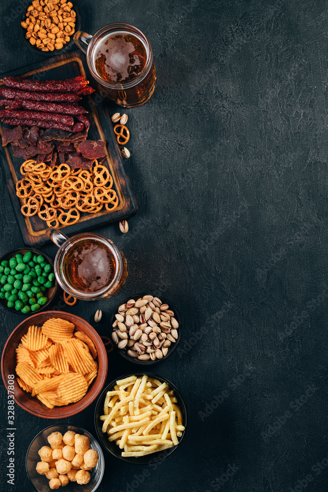 Two mugs of light beer and big assortment of beer snacks on the table, free space for text design. Oktoberfest food, pub concept Two mugs of light beer and big assortment of beer snacks on the table, free space for text design. Oktoberfest food, pub concept