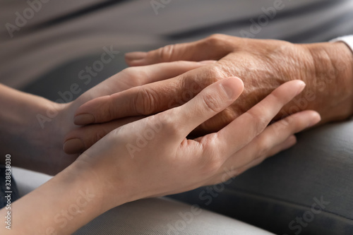 Close up of caring adult daughter hold senior mom hands show love and support, supportive grownup young woman child comfort caress mature mother, give help and assistance, family bonding concept
