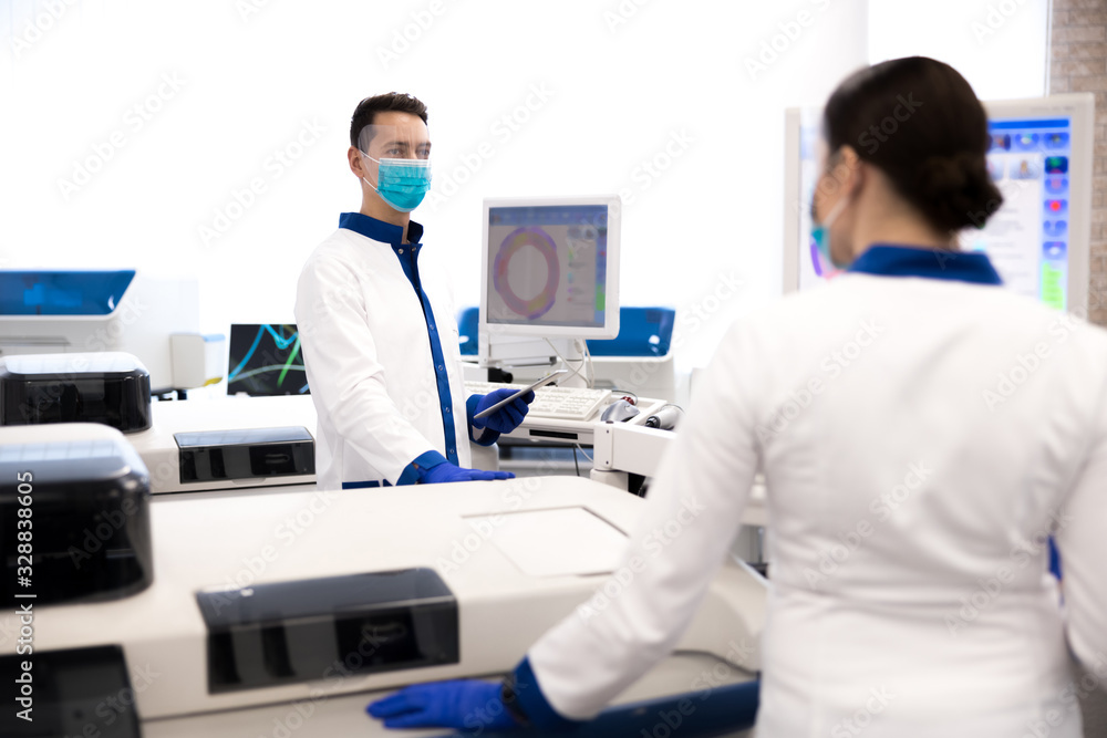 Scientists in protective medical masks working in laboratory Scientists in protective medical masks working in laboratory