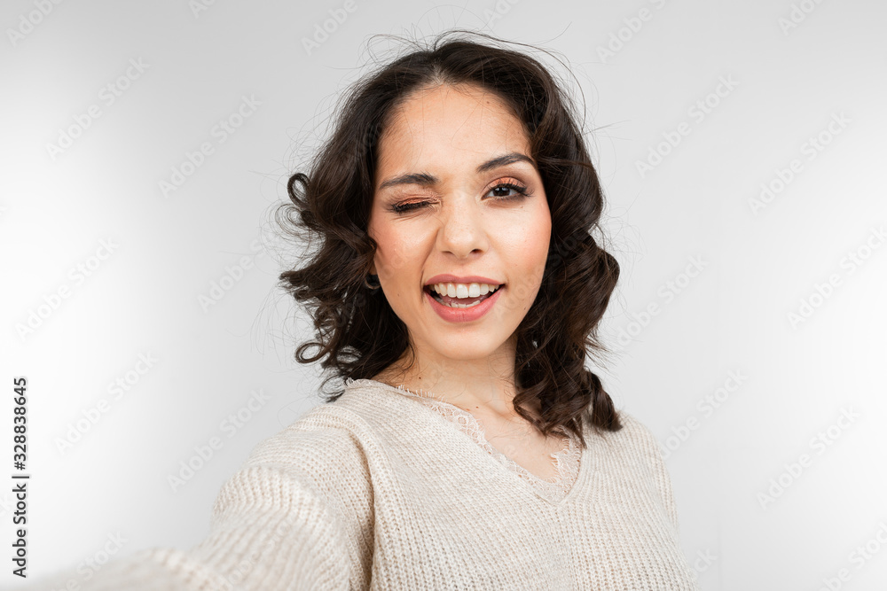 young woman model taking selfie while grimacing on gray studio background young woman model taking selfie while grimacing on gray studio background