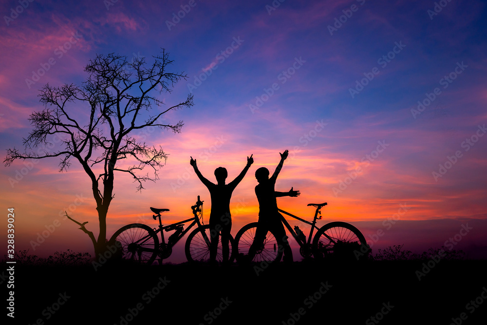 Couple cyclist and Bicycle silhouettes on the dark background of sunsets.cyclist with a bike enjoys the view of sunrise.