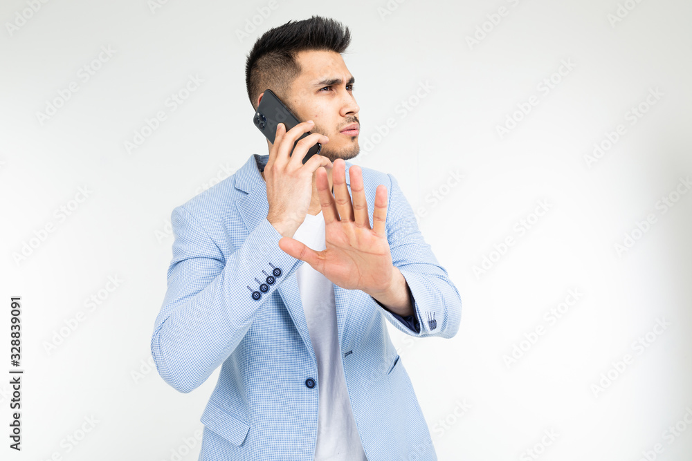portrait of a businessman in a blue jacket talking seriously with partners on the phone with the expression do not interrupt on a white background portrait of a businessman in a blue jacket talking seriously with partners on the phone with the expression do not interrupt on a white background
