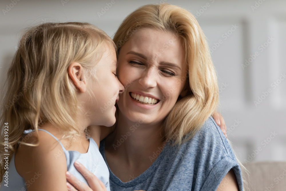 Overjoyed young mother and cute little preschooler daughter feel playful hugging cuddling at home, happy mom and small girl child play have fun enjoy family weekend together in living room