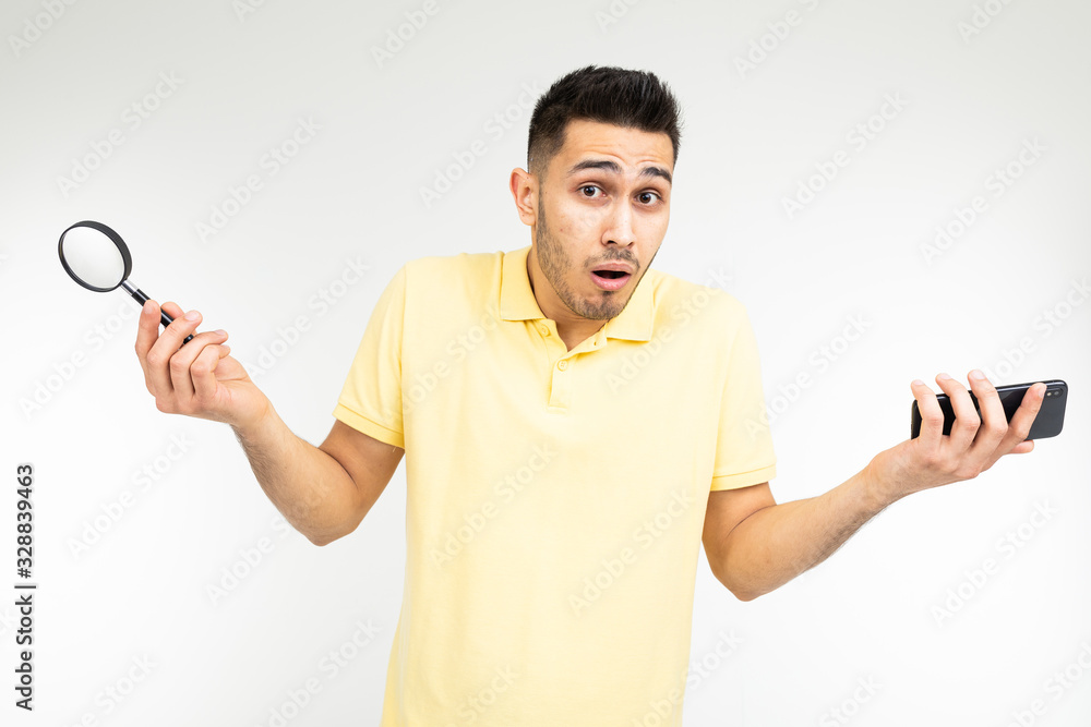 handsome man with low vision holds a magnifier and a smartphone in his hand on a white background with copy space handsome man with low vision holds a magnifier and a smartphone in his hand on a white background with copy space