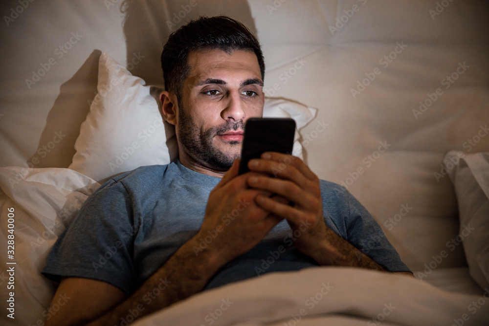 Man with smartphone in bed stock photo Man with smartphone in bed stock photo