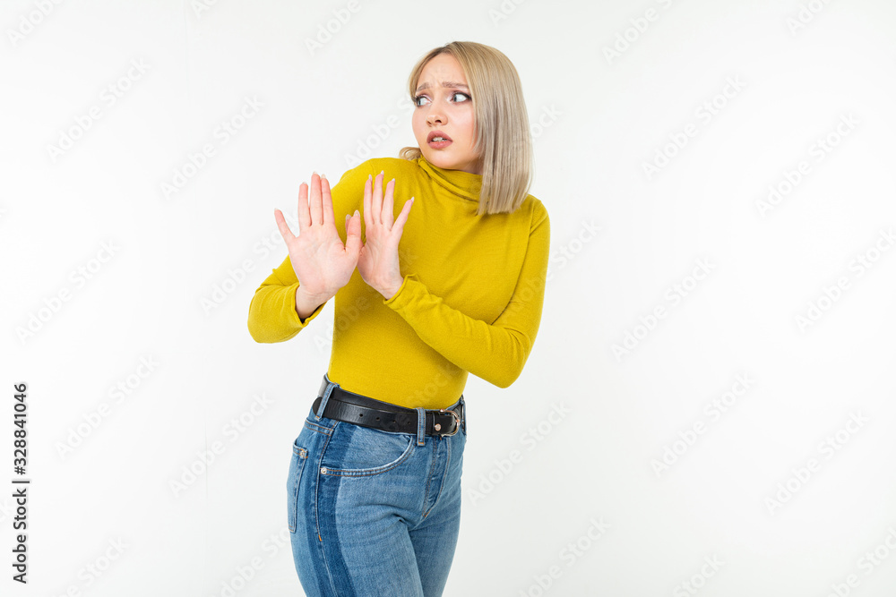 sexy blond girl in a tight-fitting lemon blouse and jeans waves her hands in denial on a white background sexy blond girl in a tight-fitting lemon blouse and jeans waves her hands in denial on a white background