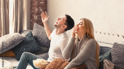 Fotografi Laughing man and woman enjoying comedy show on TV at home, empty space