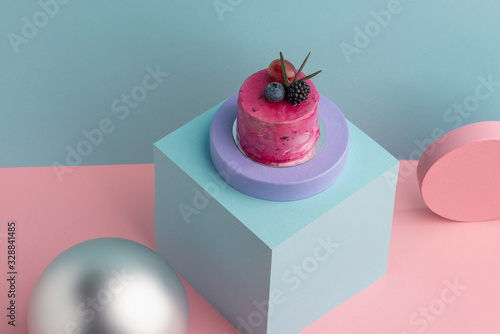 Pink mousse cake with blueberry and blackberry on blue background