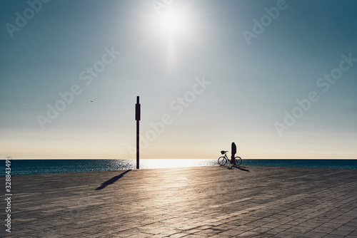 Photography backlit silhouette of boy with a bicycle on the beach in barcelona