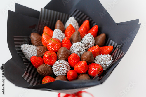 Tasty ripe strawberries in brown chocolate in the form of a bouquet on a white background. Top view