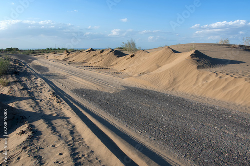 Nature conquers civilization. Sand-covered road in the middle of nowhere. Kyzylkum desert, Uzbekistan, Central Asia.