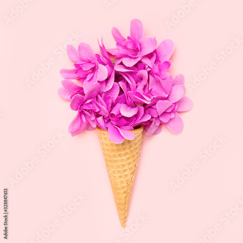 Ice cream cone with flowers on pink background.Top view.Copy space.Spring flowers concept