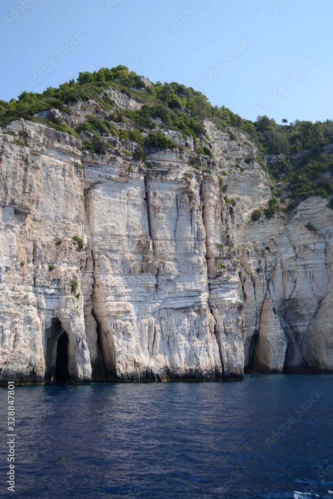 Vertical photo of some entries in blue caves in Paxos, Greece