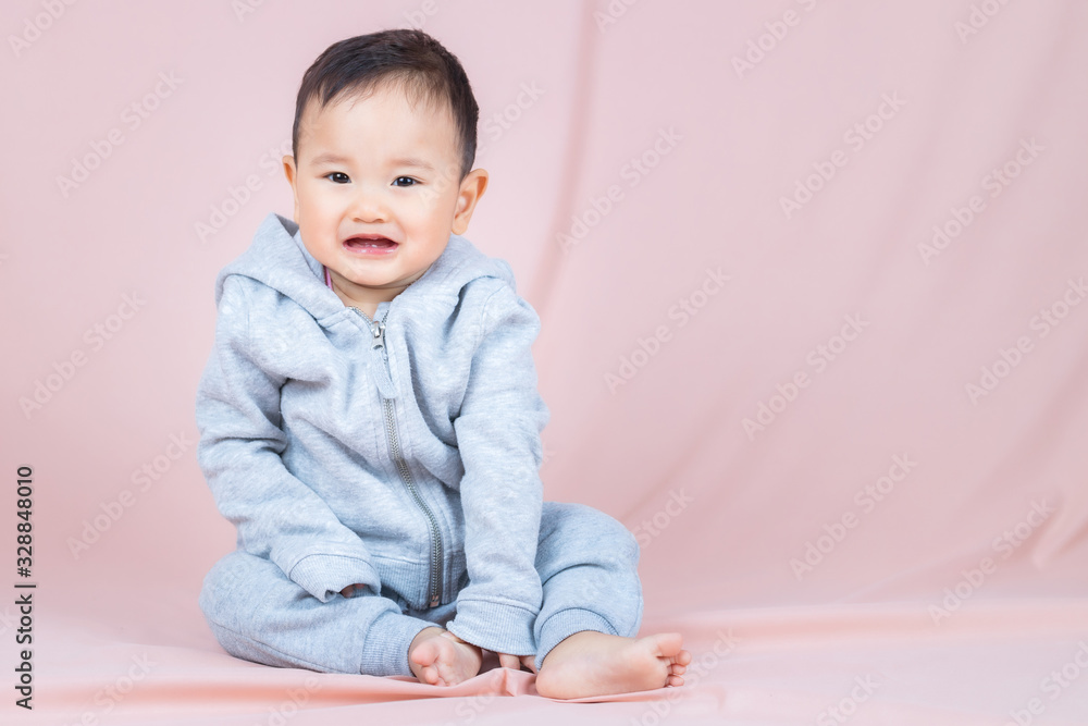 Asia baby boy wearing gray shirt and pants, sitting on floor and peach background. Asia baby boy wearing gray shirt and pants, sitting on floor and peach background.