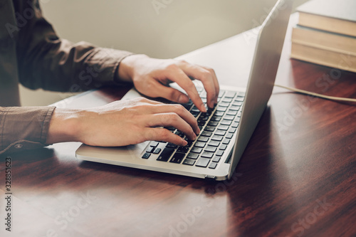 business man hand texting laptop on wooden table