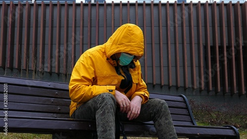 Sick man in medical mask falls on a bench without strength from illness © PaulShlykov