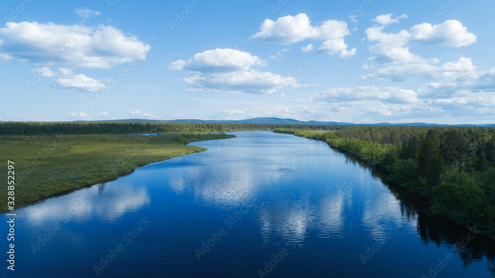 River with blue sky and clouds reflected in water in summer day. Lapland. 