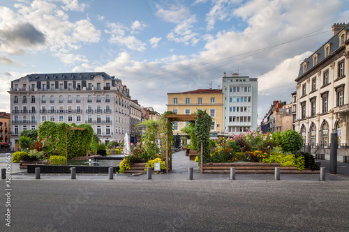 Beautiful, colorful natural oasis on Place de Jaude city square of Clermont Ferrand in France, traditional architecture and colorful cloudy sky photo