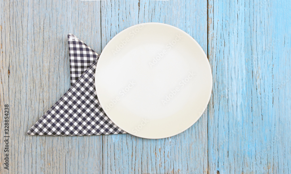 white plate on tablecloth on wood table background white plate on tablecloth on wood table background