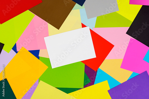 A multi-colored kaleidoscope of colored sheets of paper scattered chaotically in the style of ruled, beautiful chaos on a colorful background with a white sheet for notes.