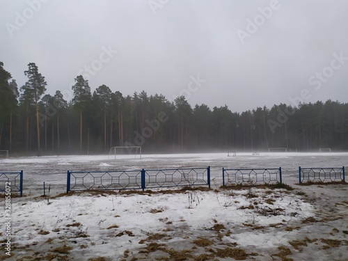 Gloomy rainy day in forest stadium with gates and mist in early spring with melting snow
