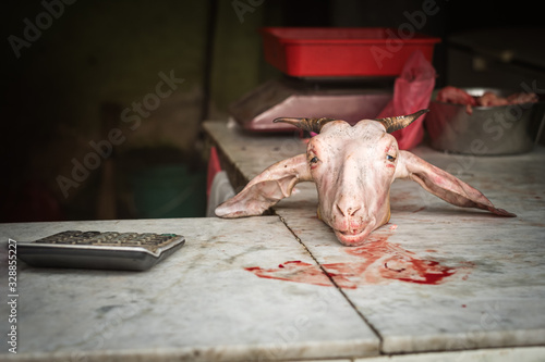 Animal head in butcher shop with calculator and blood