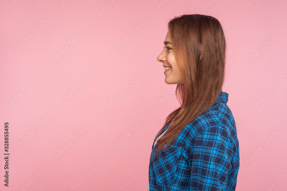 Profile of cheerful good-natured girl in checkered shirt smiling and looking at side copy space, satisfied contented with life, rejoicing positive news. indoor studio shot isolated on pink background Profile of cheerful good-natured girl in checkered shirt smiling and looking at side copy space, satisfied contented with life, rejoicing positive news. indoor studio shot isolated on pink background