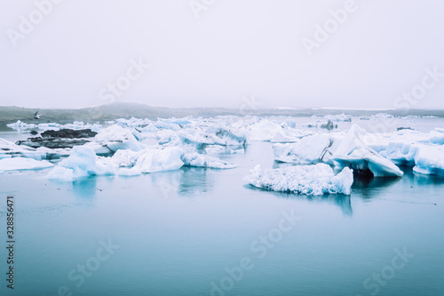Bright white glaciers covered with dense fog in the blue waters of Jokulsalron glacial lake in Iceland