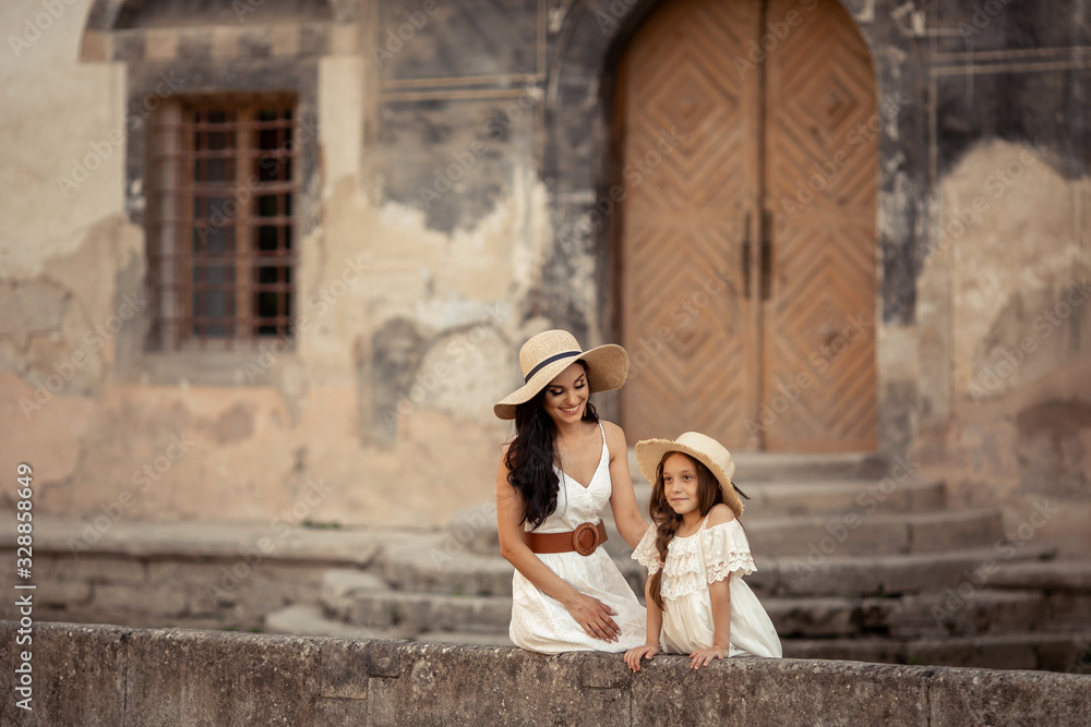Young beautiful mother of eastern appearance walks with her daughter on the ancient streets of the Mediterranean city.